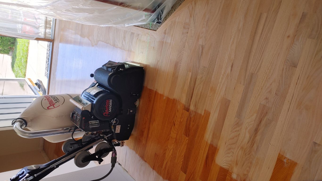 Wood floor being refinished with equipment in a home.