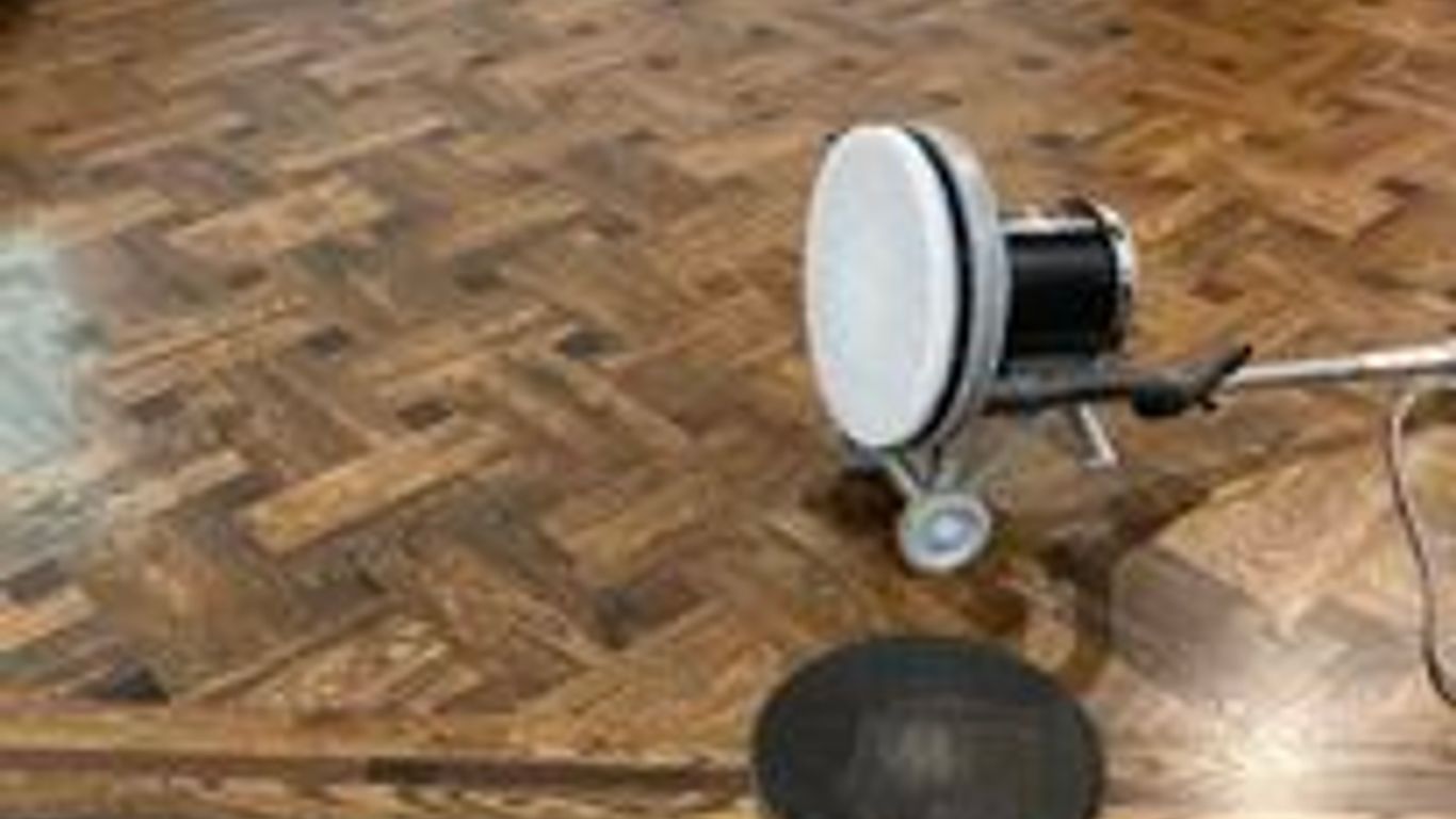 Polished wooden floor with a cleaning machine in use.