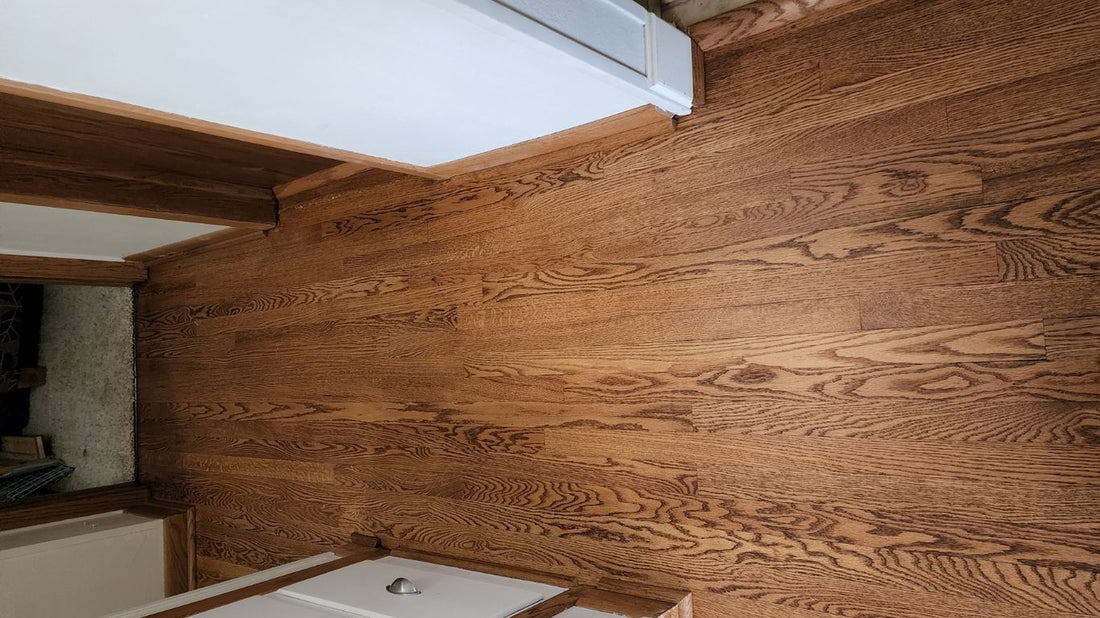 Wooden floor in a hallway with white cabinetry visible.