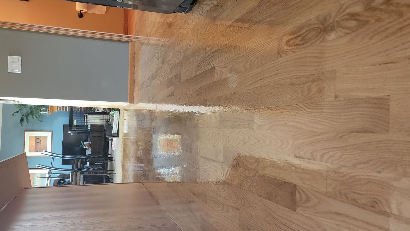 Shiny hardwood floor reflecting light in a spacious corridor.
