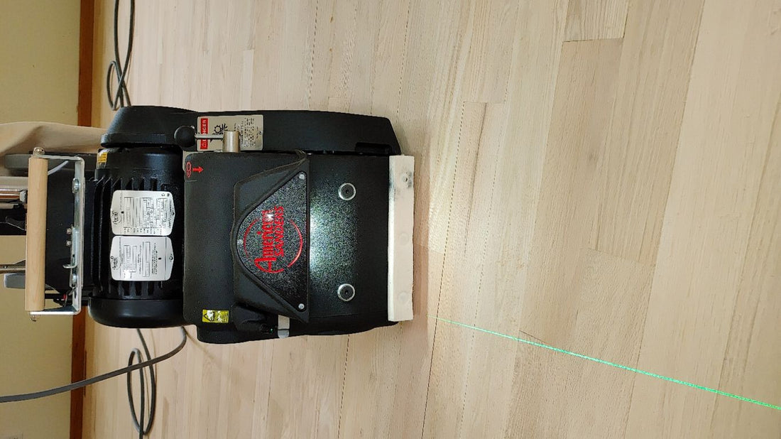 A sanding machine with a laser line on wooden flooring.